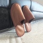 brown hotel slippers on carpet near sofa comfortable guest room hospitality slippers