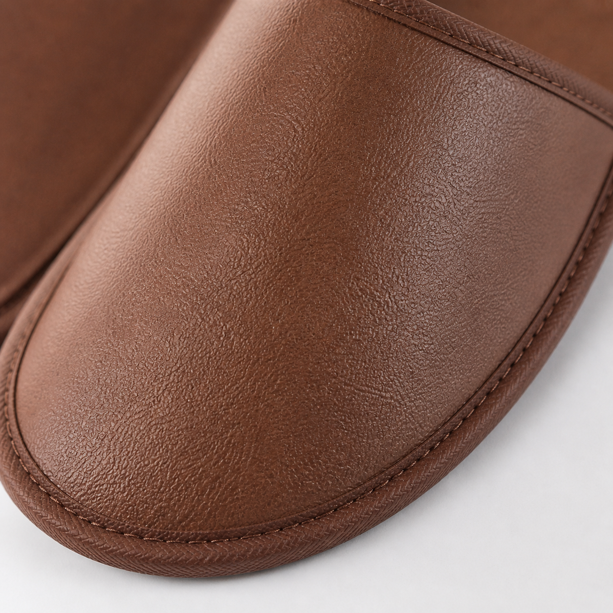 close up texture of brown PU leather hotel slippers durable material stitching detail