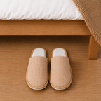 Corduroy hotel guest slippers beside hotel bed